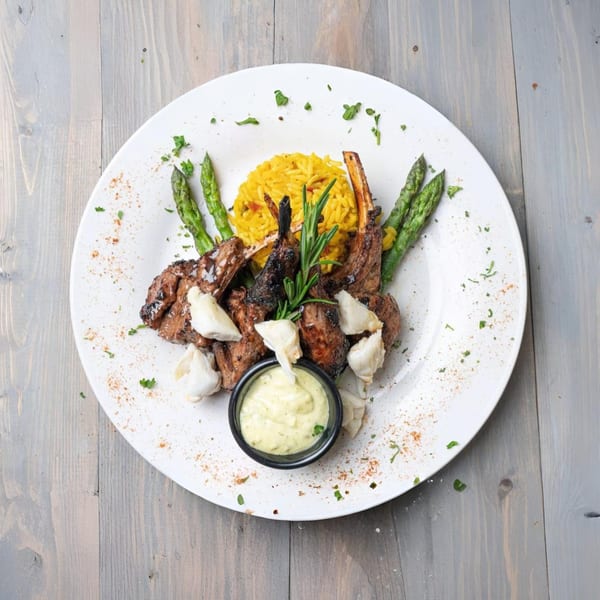 Grilled lamb chops with yellow rice, asparagus, crab meat, and a creamy green sauce.