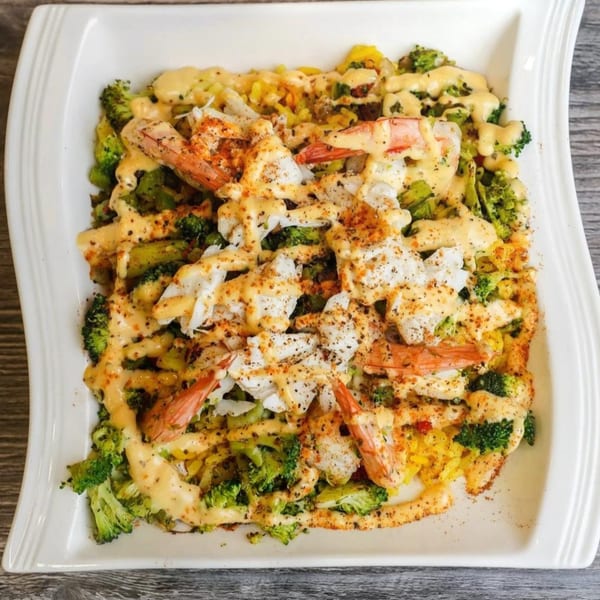 Halal shrimp and crab meat dish with broccoli, rice, and creamy sauce, topped with spices.
